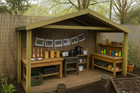 Children's playhouse with pretend kitchen and outdoor elements in a garden setting.