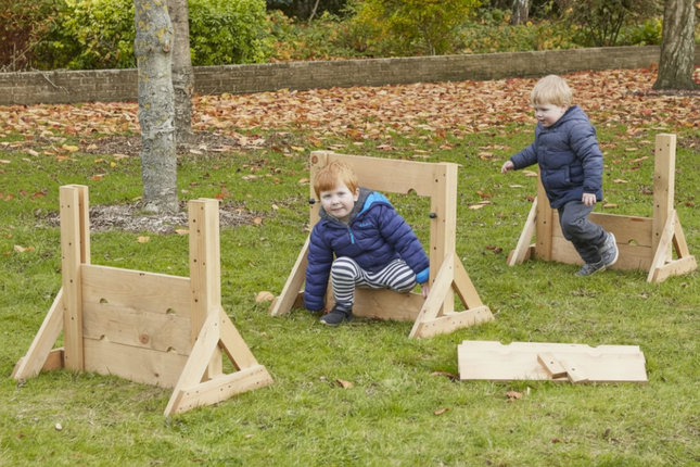 Two children playing with wooden wall in a park