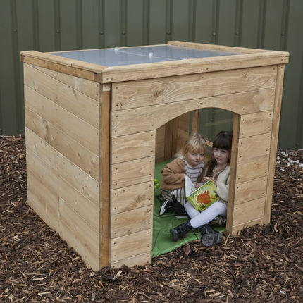 Two children playing inside a wooden playhouse on mulch.