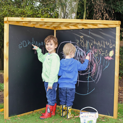 Two children drawing on an outdoor chalkboard with a wooden frame.