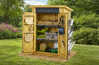 Wooden writing shed with various supplies inside, outdoors on a grassy area.