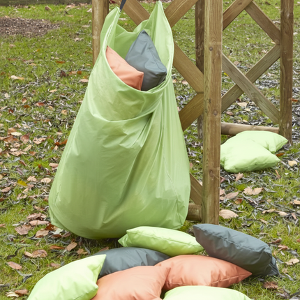 Green laundry bag with pillows on a grassy ground