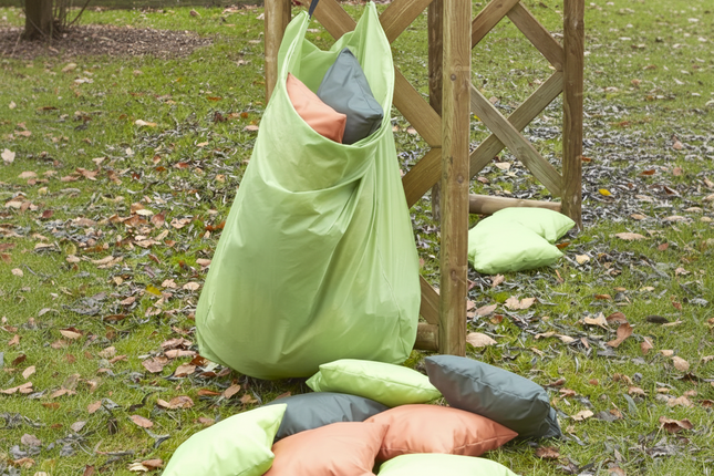 Green laundry bag with pillows on a grassy ground