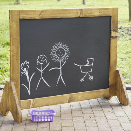 Chalkboard with stick figure drawings outdoors on a sunny day