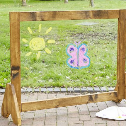 Wooden frame with child's drawings of a sun and butterfly on a grassy background