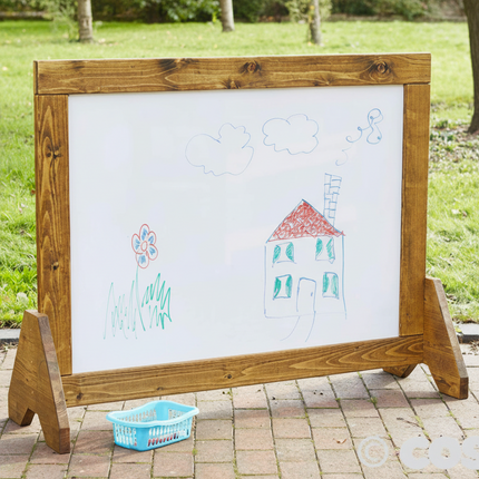 Wooden outdoor whiteboard with children's drawings on a grassy background