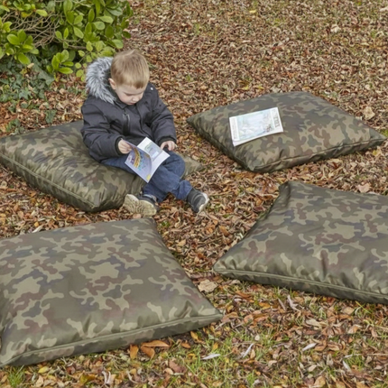 Child sitting on camouflage-patterned cushions outdoors