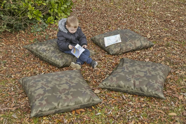 Child sitting on camouflage-patterned cushions outdoors