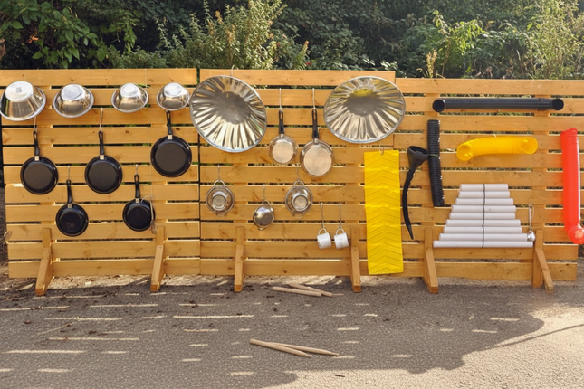 Wooden wall with various kitchen utensils including pots, pans, and a xylophone.
