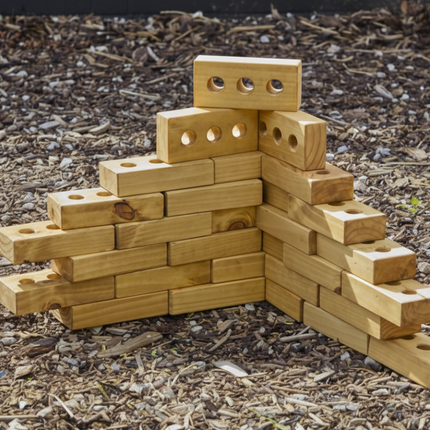 Wooden block sculpture of a bear on a mulched surface
