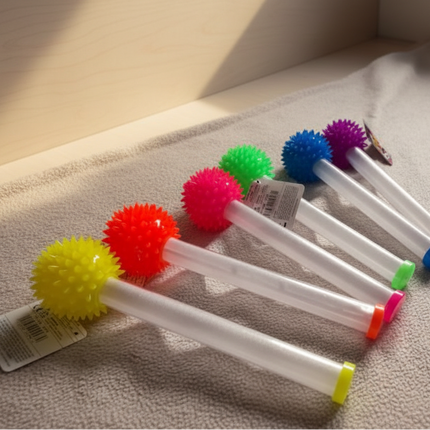 Colourful spikey balls on translucent handles lying on a textured surface