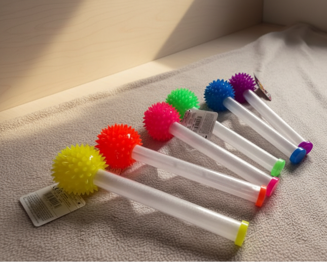 Colourful spikey balls on translucent handles lying on a textured surface