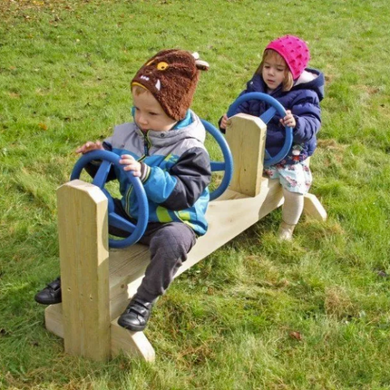 Two children playing on a seesaw in a grassy area