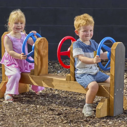 Two children playing on a wooden playground structure with colorful handles.