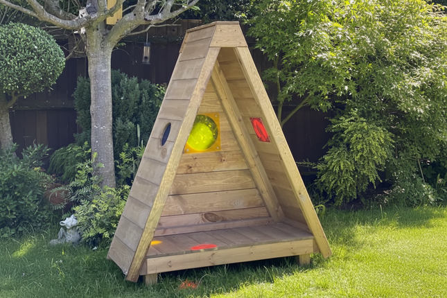 Wooden playhouse with colorful windows in a garden setting
